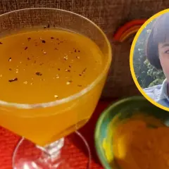 Pyszny koktajl z kurkumą, doprawiony pieprzem, obok miseczka z kurkumą i uśmiechnięta kobieta.