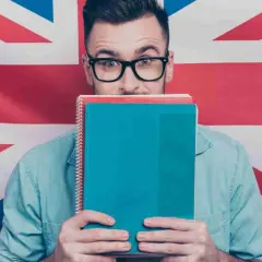 Studente con quaderni davanti al volto, sullo sfondo la Union Jack. Chissà se impara come si dice "venerdì" in inglese.