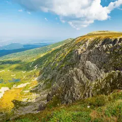 Widok na skaliste zbocze i zieloną dolinę z jeziorami. W oddali widać miasto. To krajobraz ze śnieżnych kotłów, ukazujący ich imponującą wysokość.