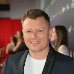 Uśmiechnięty Rafał Brzozowski na ściance. Wiele osób zastanawia się, ile lat ma Rafał Brzozowski, ale na zdjęciu tego nie widać.