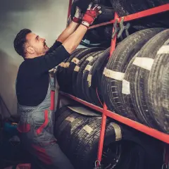 Mechanik w czerwonych rękawiczkach układa opony. Czy to Laufenn? Co to za firma?