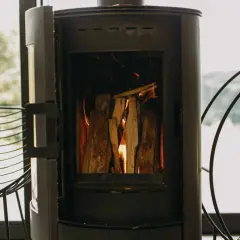 Poêle à bois allumé, avec une prise d'air poele à bois obligatoire pour une combustion optimale. Le feu crépite joyeusement.
