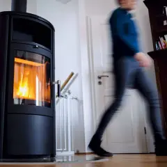Ein Mann eilt an einer brennenden Holzheizung vorbei. Angesichts des möglichen Holzheizung Verbots 2030, wird diese Heizform bald Geschichte sein.