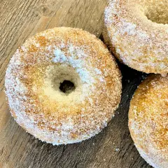 Trois donuts dorés, saupoudrés de sucre, prêts à être dégustés. Une recette donuts simple et gourmande.