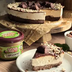 Pyszne ciasto z mascarpone, udekorowane czekoladą i orzechami. Obok słoik pasty z orzechów laskowych.