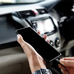 Ręce podłączają telefon do radia samochodowego, aby dołożenie bluetooth do radia samochodowego było proste.