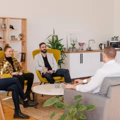 Grupa osób dyskutuje o tym, co to jest RODO, siedząc w nowoczesnym biurze.