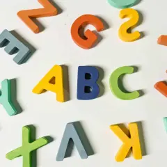 Kolorowe, drewniane litery układają się w napis "ABC", idealne do nauki angielskiego na poziomie a1.