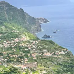 Grüne Hänge mit kleinen Häusern, die sich an die Küste schmiegen. Ein malerischer Anblick, der zu den Madeira Geheimtipps gehört.