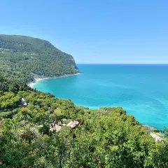 Vista mozzafiato sulla costa marchigiana, un gioiello tra le 10 cose da vedere nelle Marche. Mare turchese e verde lussureggiante.