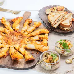 Un apéro réussi : tarte feuilletée en forme de soleil, mini sandwichs, verrines et coupes de champagne. Idéal pour savoir quoi apporter pour une invitation à un apéro.