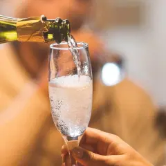 Ein Glas wird mit sprudelndem Cremant gefüllt. Was ist ein Cremant? Ein feiner Schaumwein, perfekt für besondere Anlässe.