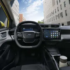 Vue du **ford puma interieur** moderne avec écran tactile, volant multifonction et tableau de bord numérique. La ville s'affiche à travers le pare-brise.