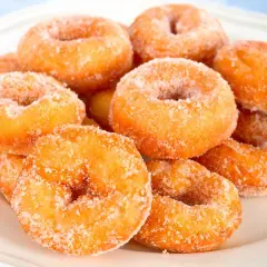 Montón de rosquillas caseras de toda la vida, doradas y espolvoreadas con azúcar.