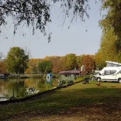 Jesień na Węgrzech. Kamper zaparkowany nad jeziorem, w tle kolorowe drzewa i mała chatka.