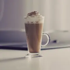 Jak zrobić latte macchiato? Wysoka szklanka z kawą, mlekiem i bitą śmietaną, posypana kakao. Idealny napój na chłodne dni.