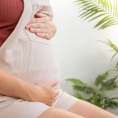 Czekając na poród, gdy szyjka macicy ma 2 cm, kobieta w ciąży trzyma się za brzuch.