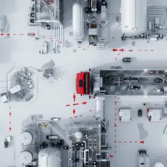 Eine rote LKW-Flotte optimiert die milk run logistics auf einem Fabrikgelände mit komplexen Rohrleitungen und Behältern.