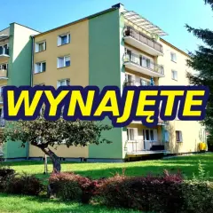 Blok mieszkalny z balkonami, zielony teren. Napis "WYNAJĘTE" sugeruje, że szukasz mieszkań do wynajęcia Zamość.