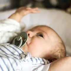 Niemowlę z niebieskimi oczami i smoczkiem, jego czoło jest ciepłe, co świadczy o prawidłowej temperaturze.
