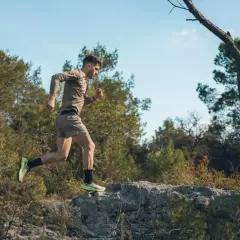 Mężczyzna w sportowym stroju biegnie po kamienistym terenie wśród drzew. To jego trening biegowy metodą Skarżyńskiego.
