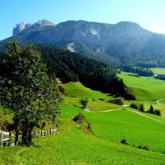 Verdi colline e montagne maestose incorniciano i pittoreschi paesi del Val di Funes, con un sentiero che serpeggia tra prati lussureggianti.