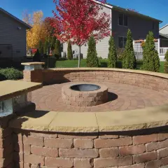A circular brick patio features an in-ground fire pit, perfect for cozy evenings.