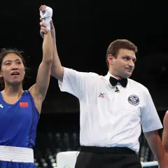 A boxer in a blue uniform with the Chinese flag raises her arm in victory as a referee holds it up. The question of what weight class is 150 in boxing is on many minds.
