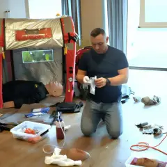 Ćwiczenie kwalifikowanej pierwszej pomocy. Instruktor przygotowuje materiały, obok manekin do nauki.