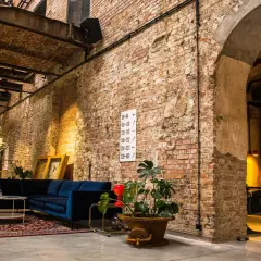 Wnętrze hotelu Cukrownia Żnin: industrialny klimat, ceglane ściany, wygodna granatowa sofa i zabytkowa maszyna.