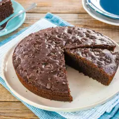 Deliziosa torta vegana al cioccolato, cosparsa di gocce e pezzi di cioccolato fondente, pronta per essere gustata.