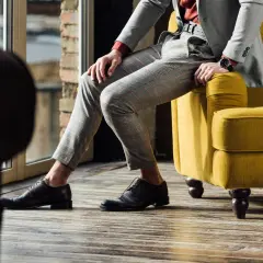 Eleganckie, brązowe oksfordy idealnie pasują do szarego garnituru w kratę. Stylowa propozycja na co dzień i od święta.