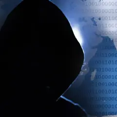 Sylwetka hakera na tle świata i kodu binarnego. Czy wiesz, phishing co to i jak się przed nim chronić?