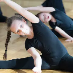 Niñas bailarinas estirando sus piernas en el suelo.