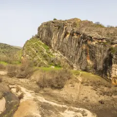 Escalada en la **ruta cañones del rio lozoya**. Un paisaje rocoso con un río seco y vegetación escasa.