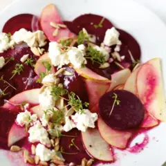 Ein köstlicher rote beete salat mit Apfelscheiben, zerbröckeltem Käse, Sonnenblumenkernen und Kresse garniert.