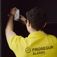 Técnico instala un sensor PIR blanco en una estantería, asegurando la protección del hogar.