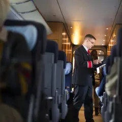 Ein Schaffner im deutschen Zugsystem prüft Tickets. Passagiere sitzen in den Reihen.