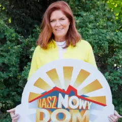 Katarzyna Dowbor z uśmiechem prezentuje tablicę z napisem "Nasz Nowy Dom".