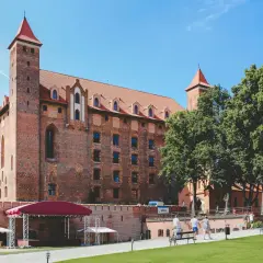Zamek w Malborku, największe województwo w Polsce, z czerwonymi dachami i wieżami, otoczony zielenią i błękitnym niebem.