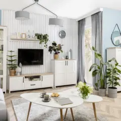 Jasny salon z białymi meblami i zielonymi roślinami. Inspiracja, jak ustawić kwiaty w salonie, by stworzyć przytulną atmosferę.