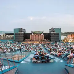 Widownia amfiteatru podczas spektaklu. Na scenie trwa przedstawienie, a za nią rozciąga się jezioro. To z pewnością niezapomniane wrażenia z puccini opery.