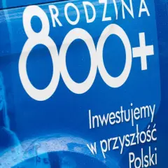 Niebieski baner z napisem "800+" i zdjęciem uśmiechniętej dziewczynki.