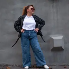 Kobieta w skórzanej kurtce i jeansach z wysokim stanem, idealnych dla puszystych. Stylowy look na co dzień.