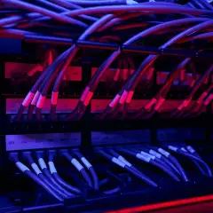 Red y azul iluminan un rack de servidores con un intrincado **cableado horizontal**.