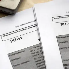 Dokumenty PIT-11 leżą obok kalkulatora. Jak rozliczyć PIT-11? To pytanie zadaje sobie wielu podatników.