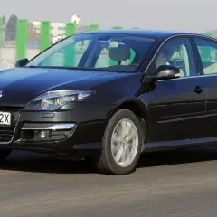 Czarny Renault Laguna 3 2.0 dCi w ruchu drogowym. Elegancki sedan z charakterystycznym grillem i reflektorami.
