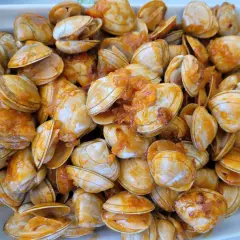 Un plato lleno de percebe gallego cocinado en una salsa anaranjada.