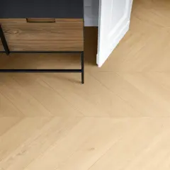 Posa di un elegante parquet in gres porcellanato effetto legno, con un motivo a spina di pesce che si estende verso una porta bianca aperta.