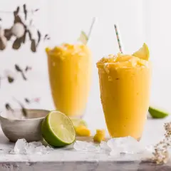 Zwei cremige Mango-Lassis mit Limette und Kokosraspeln. Perfekt nach dem getrocknete Mango einweichen.
